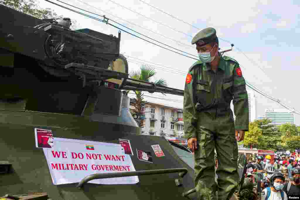 Військовослужбовець дивиться на банер із написом &laquo;Ми не хочемо військової влади&raquo;, який прикріплений до військової машини неподалік будівлі Центрального банку М&#39;янми під час акції протесту проти військового перевороту. Янгон, М&#39;янма, 15 лютого 2021 року