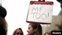 Një vajzë mban në duar një pano ku shkruan "Me Too", slogan i një lëvizjeje globale kundër abuzimit dhe ngacmimit seksual. 