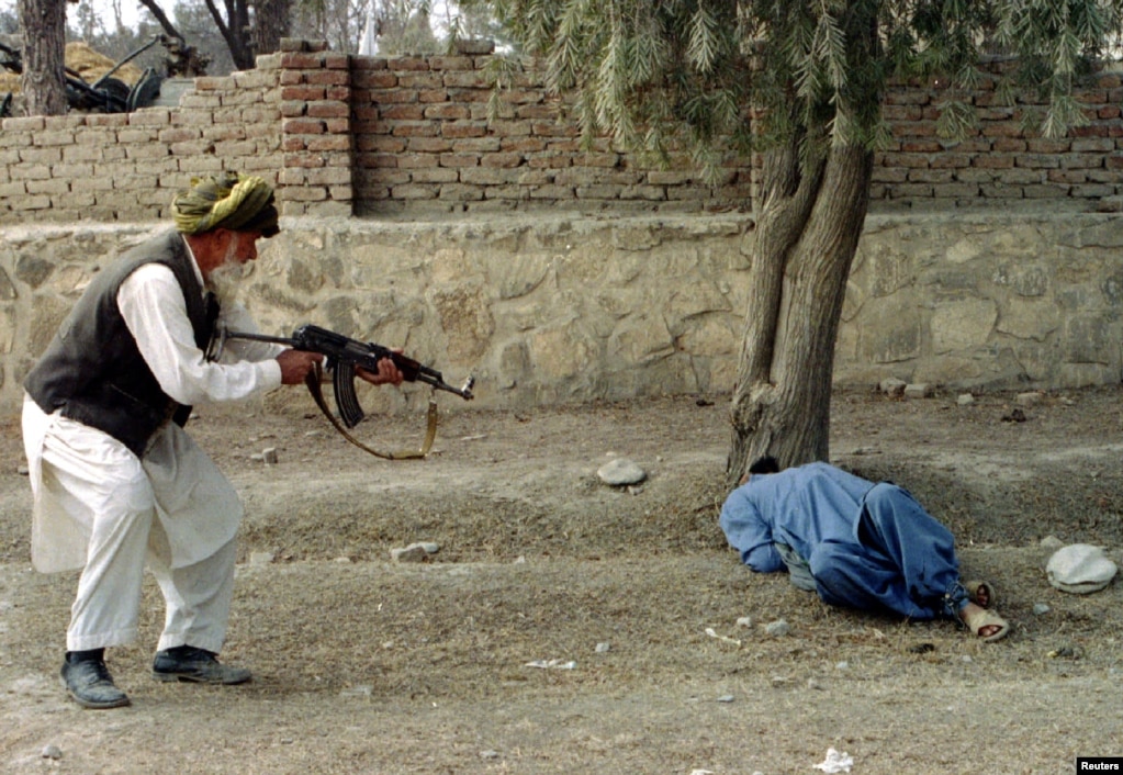 Shirin Khan (left) fires a shot from a Kalashnikov assault rifle to kill Dur Mohammad (on the ground) in the eastern Afghan town of Khost on February 9, 1996. It is one of the early qisas punishments carried out during the Taliban's first stint in power between 1996 and 2001.
