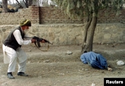 Shirin Khan (left) fires a shot from a Kalashnikov assault rifle to kill Dur Mohammad (on the ground) in the eastern Afghan town of Khost on February 9, 1996. It is one of the early qisas punishments carried out during the Taliban's first stint in power between 1996 and 2001.