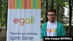 Gay activist Artiom Zavadovsky stands by a poster for Egali.md, a web platform and a video campaign in support of LGBT and gay Moldovans.