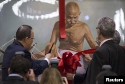 Генеральний секретар ООН Пан Ґі Мун перерізає стрічку на картині з зображенням Махатми Ганді під час спеціальної події з нагоди Міжнародного дня без насильства, організованого Постійним представництвом Індії під час Генеральної асамблеї ООН