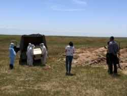 Арнайы қорғаныс киімін киген қызметкерлер коронавирустан қайтыс болған адамды жерлеу үстінде. Қараой ауылының маңы, Алматы облысы, 25 мамыр 2020 жыл.