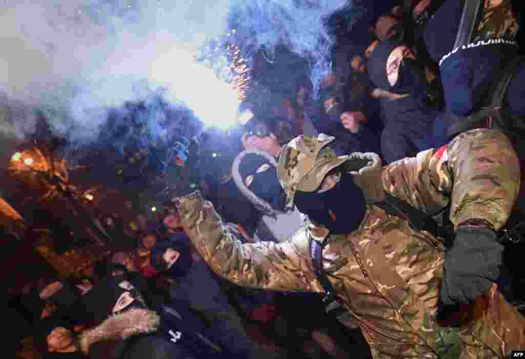 Ukrainian far-right activists throw smoke bombs at police during a protest in front of the presidential office in Kyiv. Protesters were demanding the release of "all jailed political prisoners." (AFP/Sergei Supinsky)