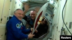 Российский космонавт Федор Юрчихин (слева) с факелом Олимпиады на борту МКС. 7 ноября 2013 года.