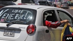 یک شهروند ونزوئلایی ساکن اکوادور با پرچم ملی در خودرویی با شعار «ونزوئلای آزاد»