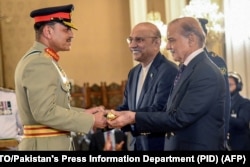 Премьер-министр Пакистана Шахбаз Шариф (справа) и президент Асиф Али Зардари (в центре) вручают фельдмаршальский жезл тогда еще главкому Сухопутных войск Пакистана, генералу Асиму Муниру на церемонии в президентской резиденции в Исламабаде. 22 мая 2025 года