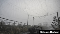 Спалений пікап під розірваною антидроновою сіткою на дорозі поблизу прифронтового міста Гуляйполе. Запорізька область, Україна, 14 листопада 2025 року