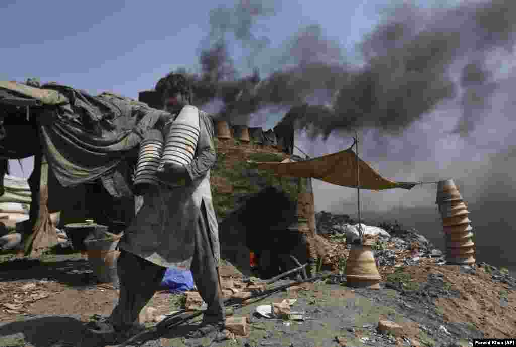 A Pakistani potter carries clay pots at a workshop in Karachi. (AP/Fareed Khan)