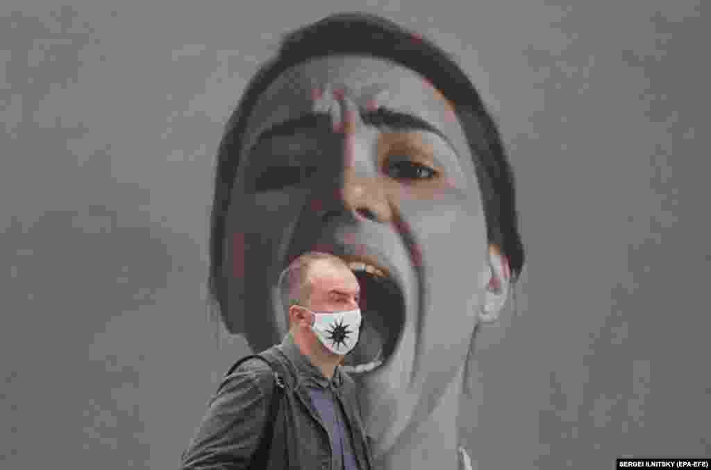 A visitor walks near a painting by Russian artist Maria Malinina.