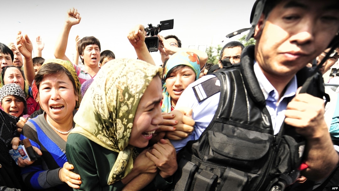Ethnic Uyghur women grab at a riot policeman as they protest in Urumqi, Xinjiang province, on July 7.