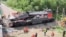 Emergency services work to remove a damaged locomotive after a road bridge collapsed onto railway tracks, derailing an approaching train in Russia's Bryansk region on June 1.
