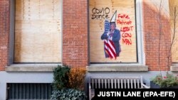 Graffiti anti-Trump pe placajul abia pus în vitrina unui magazin împotriva posibilelor violențe, cartierul SoHo, New York, SUA, 2 noiembrie 2020.