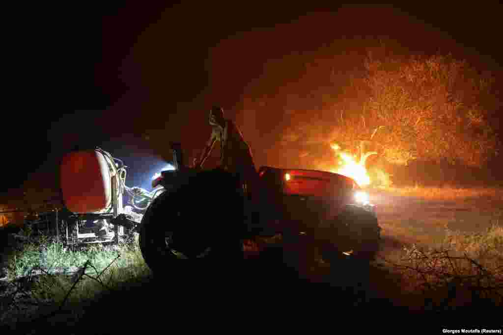 Një burrë duke qëndruar në traktorin e tij, teksa një zjarr i egër përhapej në fshatin Lasdikas, afër Olimpisë antike, në Greqi. (5 gusht)