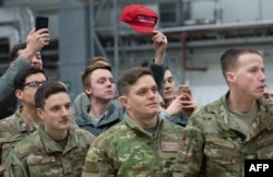 Військовослужбовець США тримає кепку з написом «Зробимо Америку знову великою», поки президент США Дональд Трамп і перша леді Меланія Трамп вітають військовослужбовців США під час зупинки на авіабазі Рамштайн у Німеччині, 27 грудня 2018 року