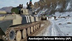 Azerbaijani soldiers sit atop their military vehicle on a road in Kalbacar, a district ringing Nagorno-Karabakh, on November 25, 2020.