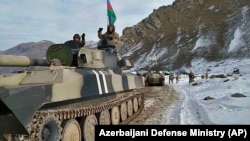 NAGORNO-KARABAKH -- Azerbaijani army soldiers sit atop of their military vehicle on a road in Kelbajar, November 25, 2020