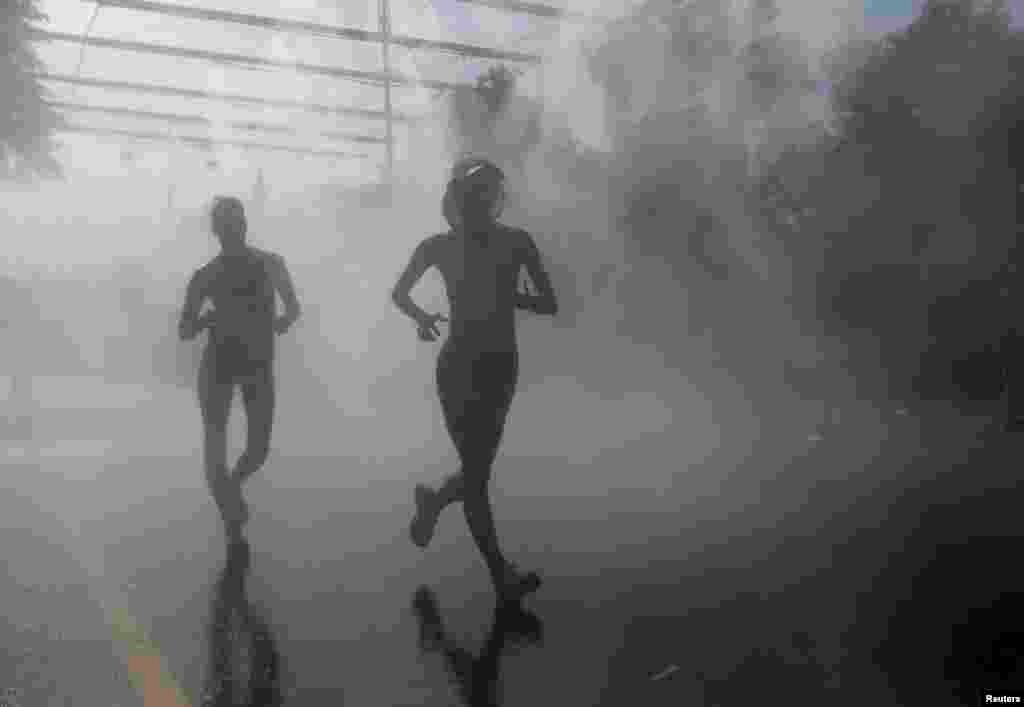 Competitors in the women&#39;s 20-kilometer race-walk final pass through cooling mist during the IAAF World Athletics Championships in Moscow. (Reuters/Maxim Shemetov)