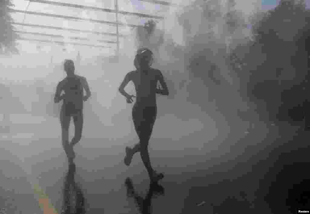 Competitors in the women's 20-kilometer race-walk final pass through cooling mist during the IAAF World Athletics Championships in Moscow. (Reuters/Maxim Shemetov)