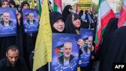 Iranians hold portraits of slain Hamas leader Ismail Haniyeh during a protest denouncing his killing, on Palestine Square in Tehran on July 31. 