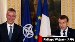 French President Emmanuel Macron (R) holds a diagram of the NATO Europe and Canada defense expenditure during a press conference with NATO Secretary-General Jens Stoltenberg in Paris, December 19, 2017