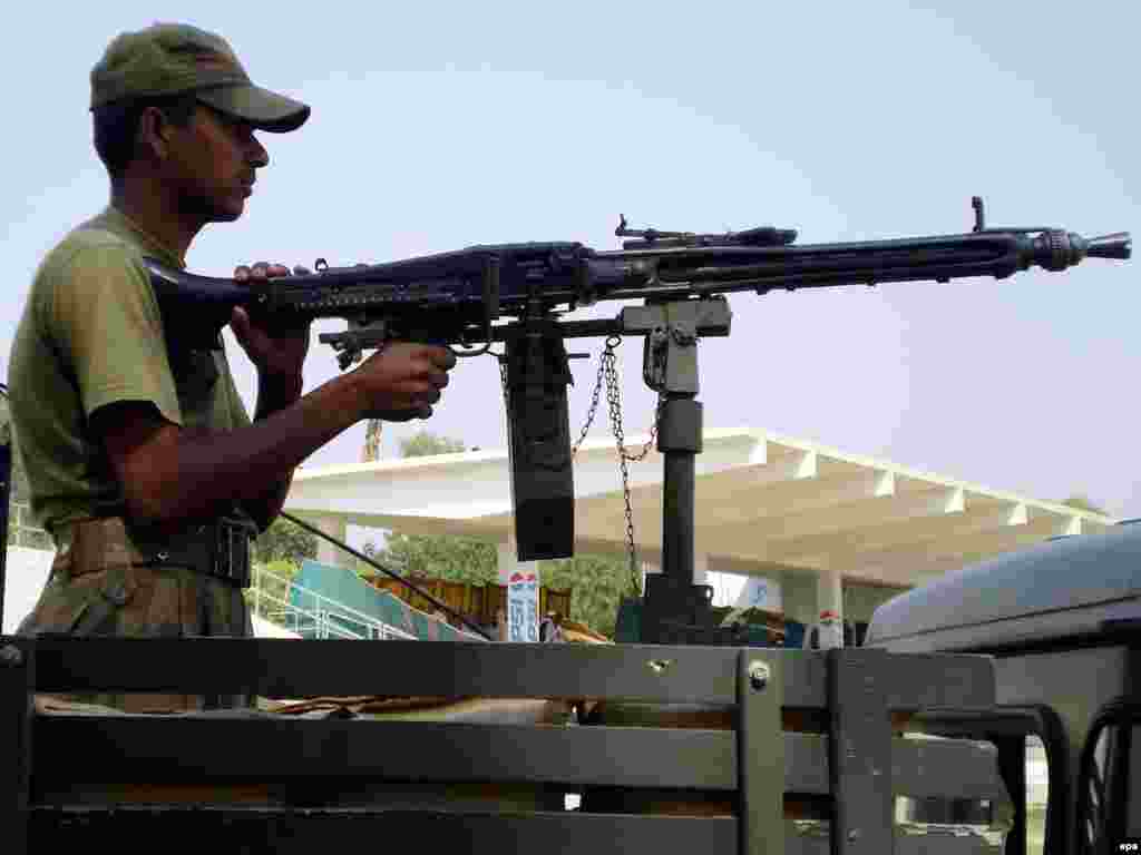 Pakistan -- A Pakistani Army soldier patrols in Dera Ismail Khan, a town of militancy-hit North-West Frontier Province, 19Oct2009 - Caption: epa01902625 Pakistani Army soldier keeps watch as people displaced from lawless South Waziristan, receive financial aid worth 5000 pkr (around 40 Euros) in Dera Ismail Khan, a town of militancy-hit North-West Frontier Province (NWFP) Pakistan on 19 October 2009. Pakistani security forces began ground offensive against Taliban and al-Qaeda insurgents in the Pakistan's lawless South Waziristan tribal region along the Afghan border. According to the United Nations, some 80,000 people had so far been displaced since May, when the Pakistani jets started airstrikes to soften militant positions.