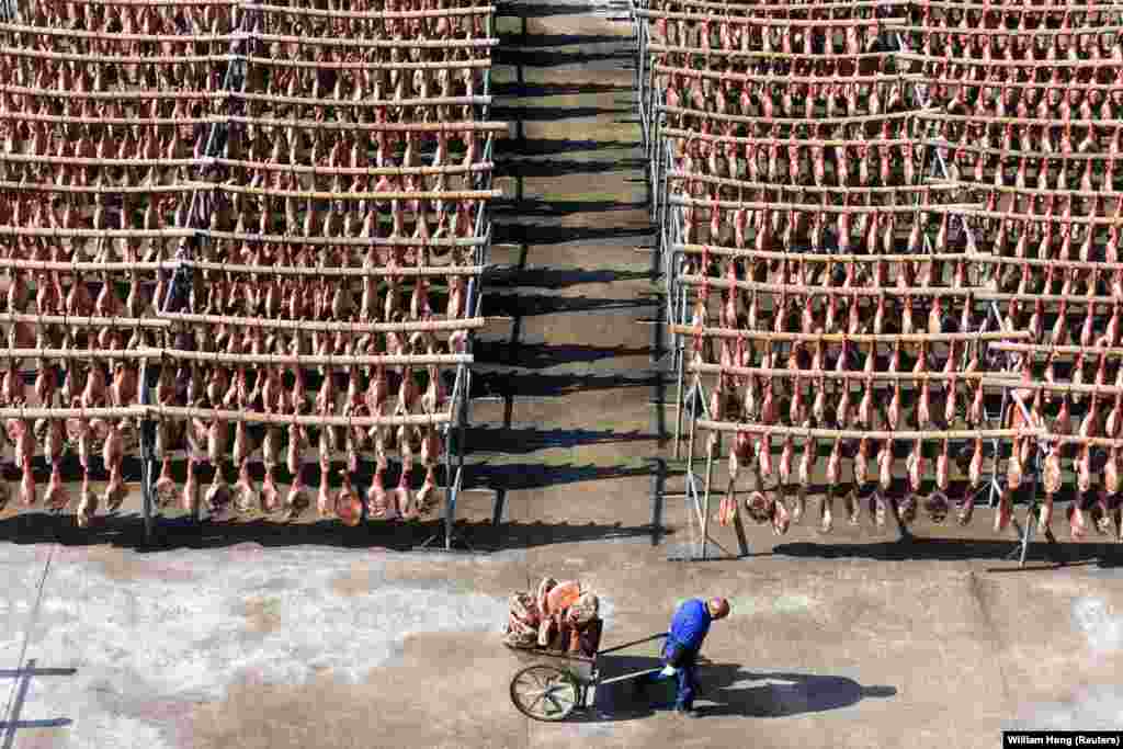 A worker pulls a cart filled with Jinhua ham at a processing facility in China&#39;s Zhejiang Province. (Reuters/William Hong)