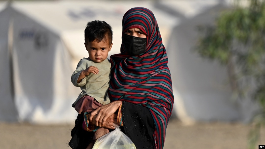 An Afghan woman holds a child as she arrives from Pakistan at a makeshift camp near the Afghanistan-Pakistan Torkham border in Nangarhar Province on April 20. An Afghan woman holds a child as she arrives from Pakistan at a makeshift camp near the Afghanistan-Pakistan Torkham border in Nangarhar Province on April 20.