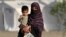 Afganistanka drži dijete dok stiže iz Pakistana u improvizirani kamp blizu afganistansko-pakistanske granice Torkham u provinciji Nangarhar 20. aprila