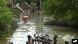 Pakistani villagers carry a motorbike as they flee their flooded homes in Badin in Sindh Province.