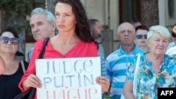 Участница траурной церемонии в Харькове, куда были доставлены тела пассажиров "Боинга", держит плакат с призывом судить Владимира Путина в Гааге.