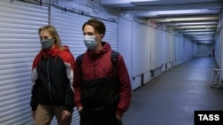 Девушка и юноша идут вдоль закрытых на карантин торговых киосков в подземном переходе на площади Советской в Симферополе