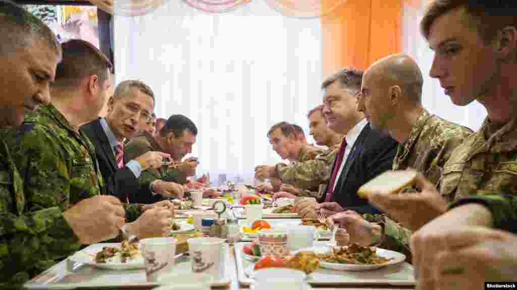 Генеральний секретар НАТО Єнс Столтенберґ (третій ліворуч) і президент України Петро Порошенко (третій праворуч) обідають на Яворівському полігоні у Львівській області. 21 вересня 2015 року