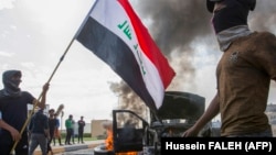 Демонстранты у сгоревшего полицейского автомобиля. Басра, Ирак, 24 ноября 2019 года.