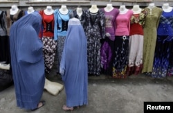 Women shop for clothes hung on mannequin displays along a street in Kabul.