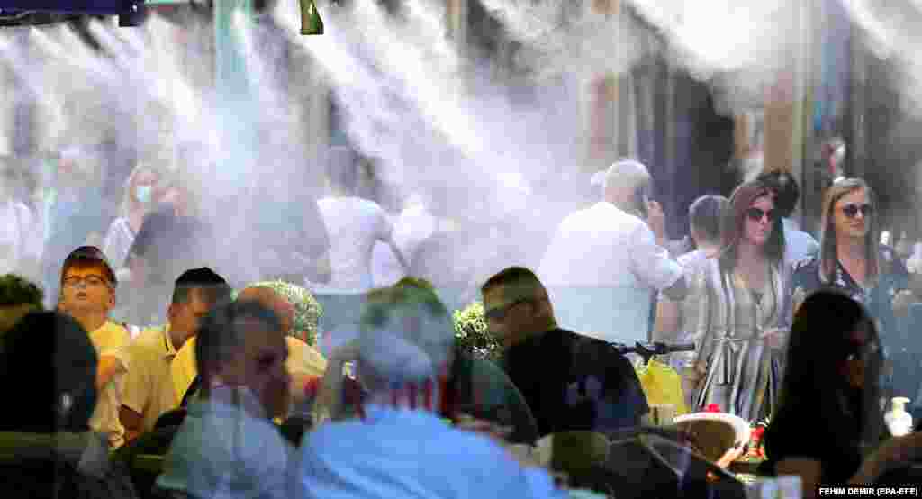 Распылители воды охлаждают гостей в кафе и людей на главной улице Сараево. 6 июля температура в боснийской столице достигла почти 30 градусов по Цельсию