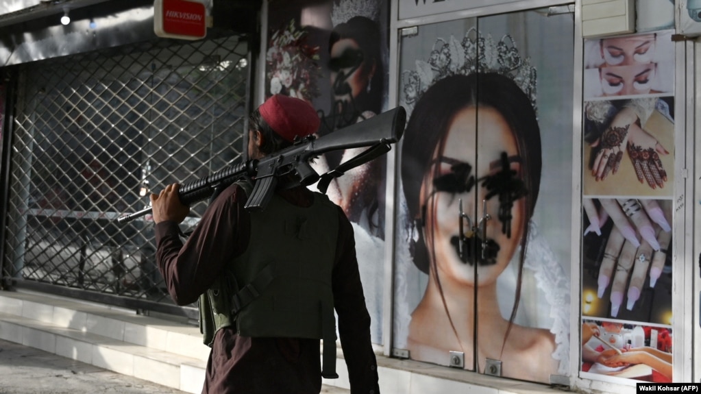 Talibanski borac prolazi pored salona za ljepotu na kojem je sprejem išaran ženski lik na fotografiji, Kabul, 18. avgust 2021.