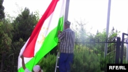 Пожилые сотрудники хукумата устанавливают флаг Таджикистана на государственном учреждении