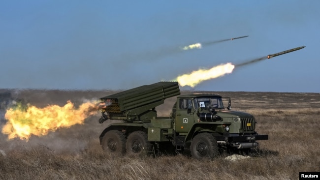 سربازان روس در جریان رزمایش‌های نظامی سال ۲۰۱۹، سه سال پیش از حمله به اوکراین، یک سامانهٔ راکت‌انداز چندگانهٔ BM-21 گراد را شلیک می‌کنند