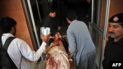 Pakistani volunteers move a man injured in a bomb attack into a hospital in Peshawar following a suicide bomb attack on a government building in Mardan on April 19.