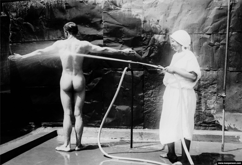 A nurse hoses down a patient in a photograph titled In The Hospital.