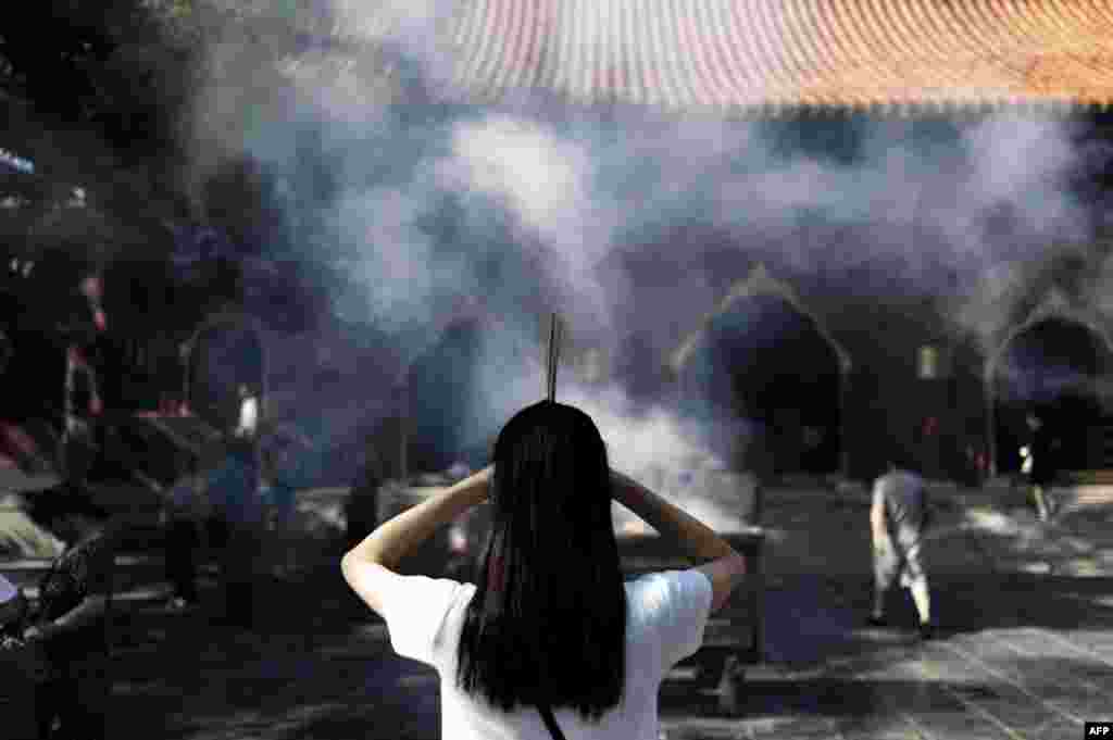 A woman holds incense as she prays at the Lama Temple in Beijing, China, on August 19. (AFP/Fred Dufour)