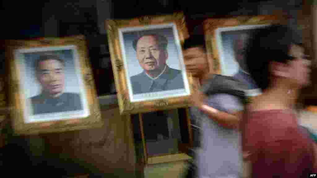 Pedestrians walk past portraits of past Chinese leaders as Beijing prepares for the 18th National Congress of the Communist Party that will see a change in the country&#39;s leadership. (AFP PHOTO/Mark Ralston)