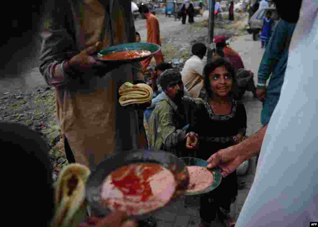 People eat food distributed by a charity outside a restaurant in Karachi, Pakistan. (AFP/Asif Hassan)