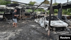 A resident stands next to burned cars at the site of a Russian drone strike on the Ukrainian city of Dnipro on July 26. 