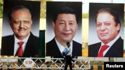 FILE: A policeman stands guard next to giant portraits of Pakistani President Mamnoon Hussain, Chinese President Xi Jinping, and former Pakistani Prime Minister Nawaz Sharif, displayed along a road in Islamabad ahead of Xi's visit in April 2015 