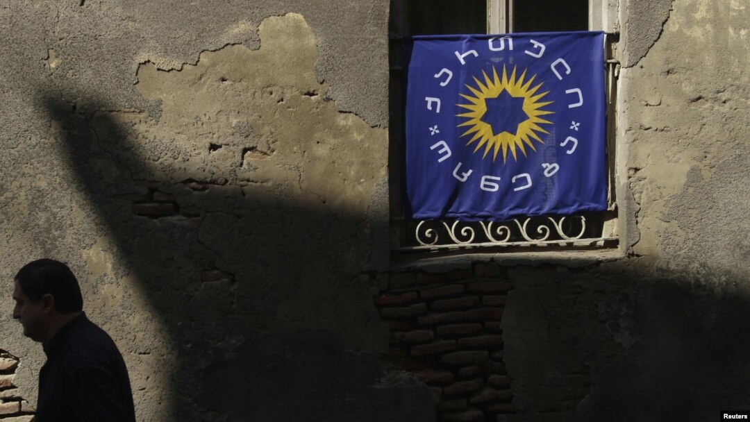 Georgia -- A pedestrian walks past a window decorated with the Georgian Dream coalition flag in Tbilisi, 03Oct2012