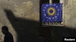 Georgia -- A pedestrian walks past a window decorated with the Georgian Dream coalition flag in Tbilisi, 03Oct2012