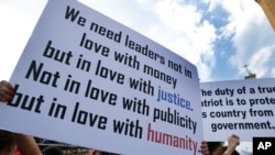 Anti-government protesters hold placards as they protest, in downtown Beirut, Lebanon, Sunday, Oct. 20, 2019. Tens of thousands of Lebanese protesters of all ages gathered Sunday in major cities and towns nationwide, with each hour bringing hundreds more 