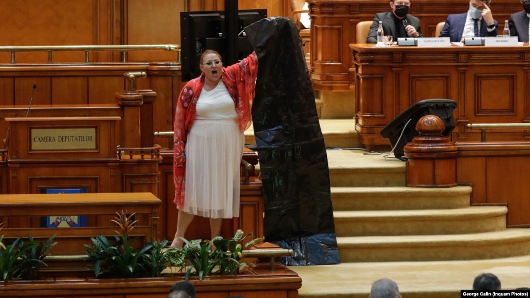 Diana Șoșoacă în Parlament, în 2021, cu un sac de gunoi, strigând că instituțiile române ucid cetățeni prin măsurile impuse împotriva pandemiei de Covid. 